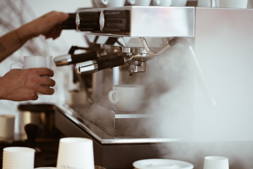 Person mit weißem Becher, der Kaffee brüht