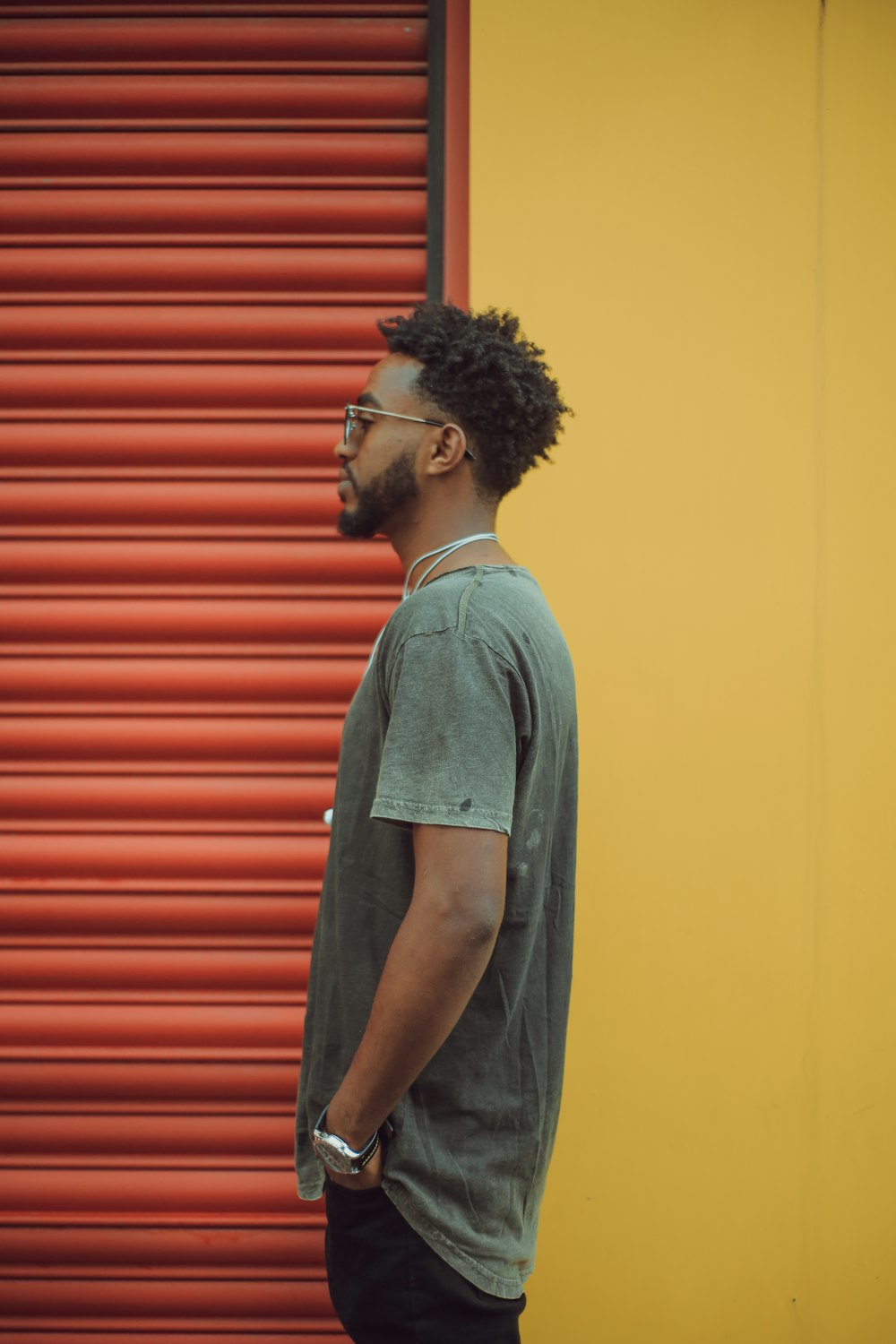 man in gray t-shirt standing near red roll up door