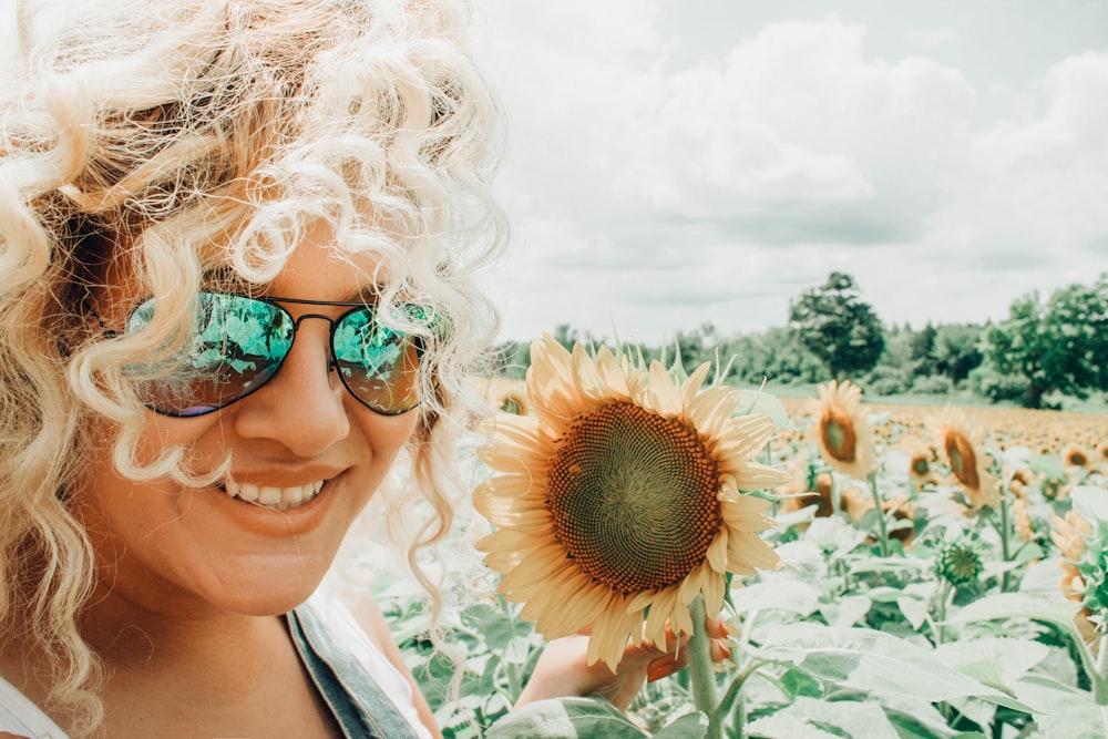 Fotografía de enfoque de mujer sosteniendo girasol