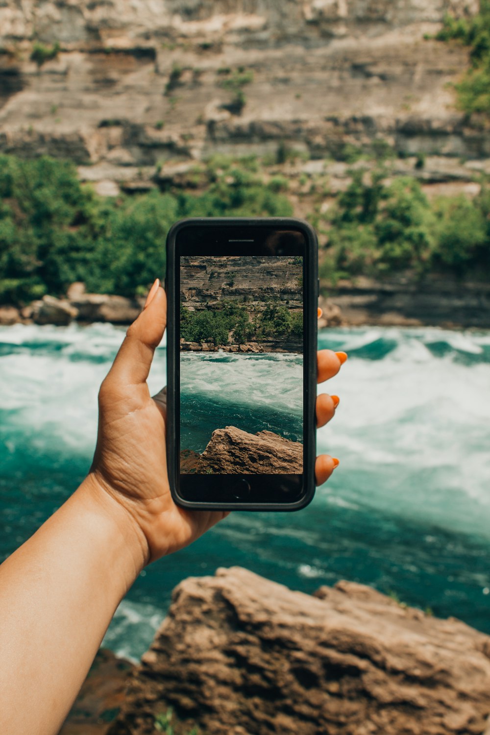 person holding black smartphone focusing body of water