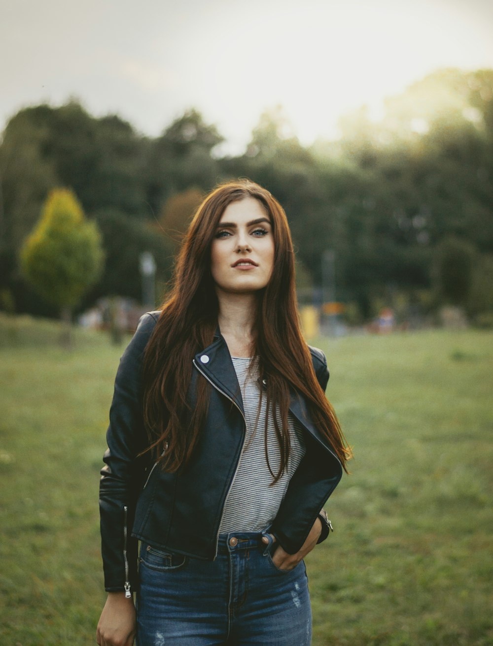 woman with hand on pocket standing on green grass field at daytime