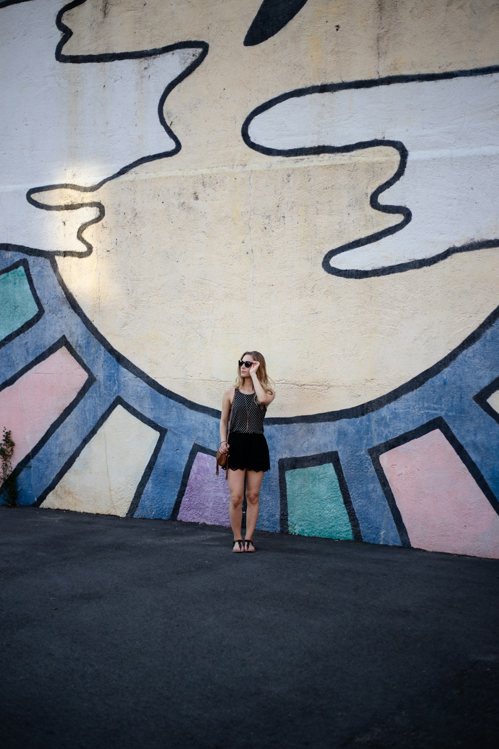 standing woman beside multicolored wall