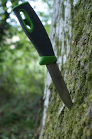 Close-up of a weathered hunting knife resting on moss-covered rocks.