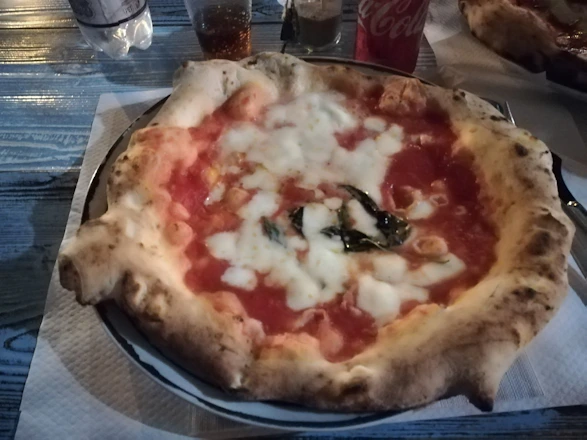 A cozy restaurant table with a delicious pepperoni pizza and a cold Coca-Cola bottle.