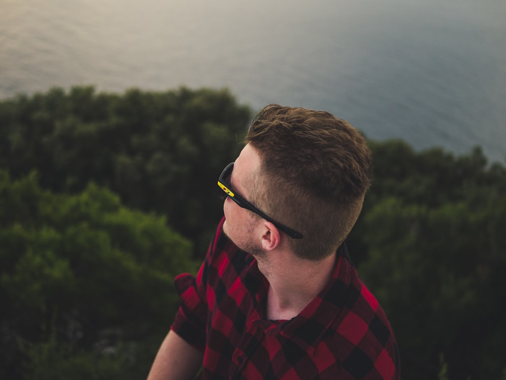 man wearing black sports sunglasses facing body of water