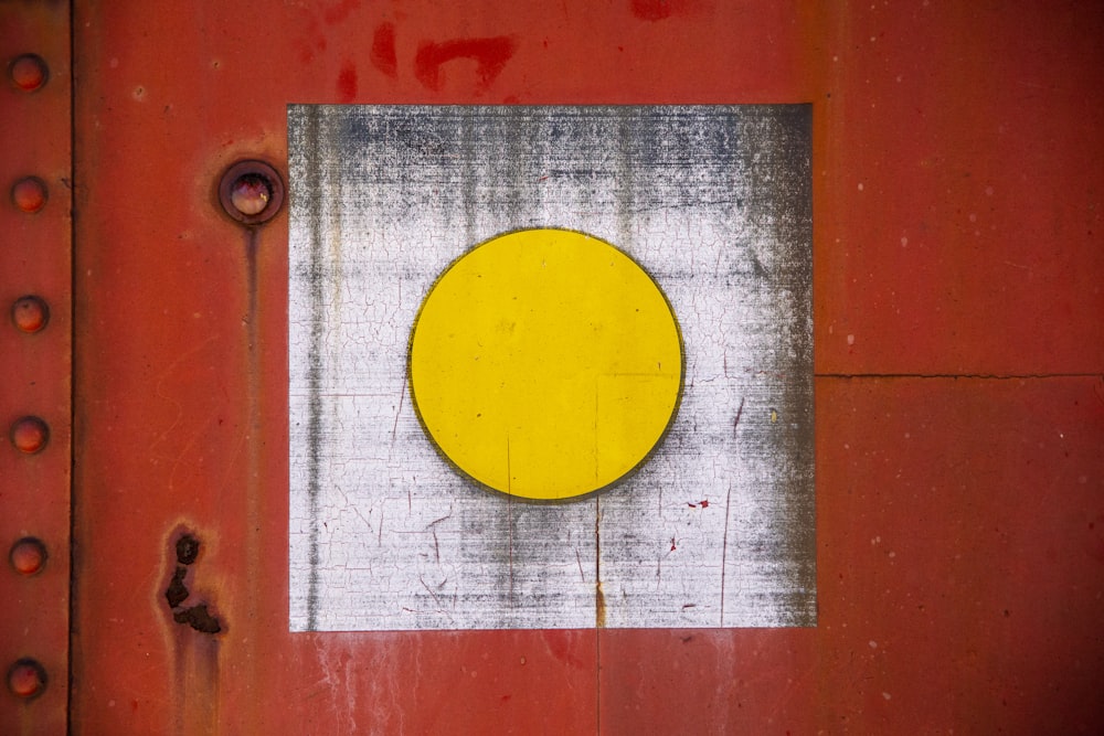 a yellow circle on a red metal surface