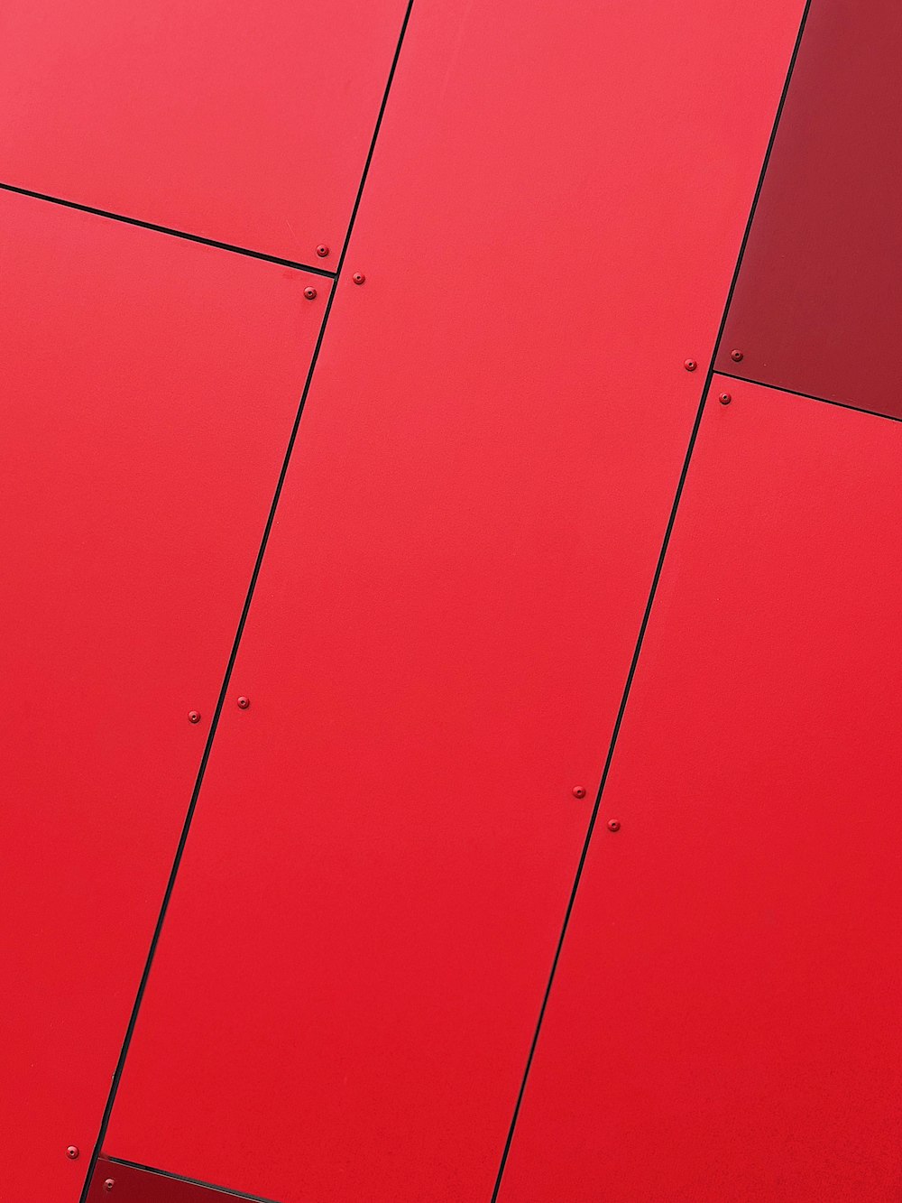 a close up of a red wall with metal rivets