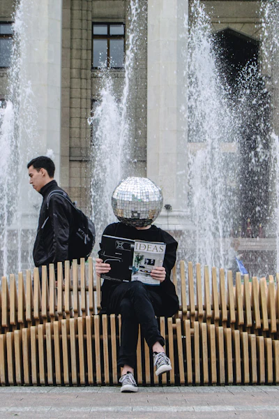 A reader on a wooden bench by a fountain in Almaty