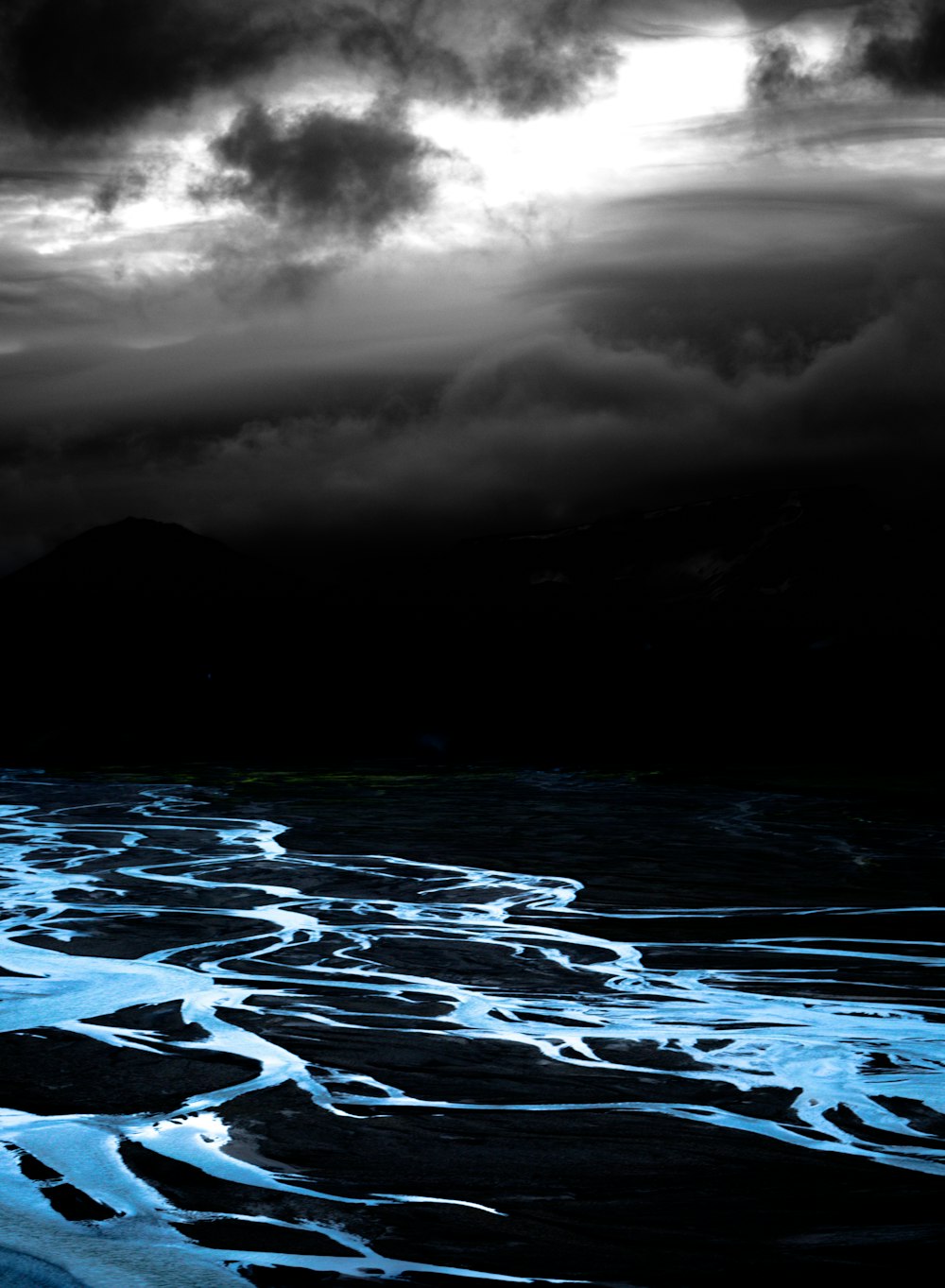 body of water under grey and black cloudy sky