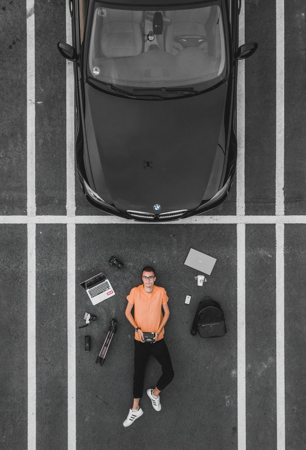 man lying on parking lot near black car