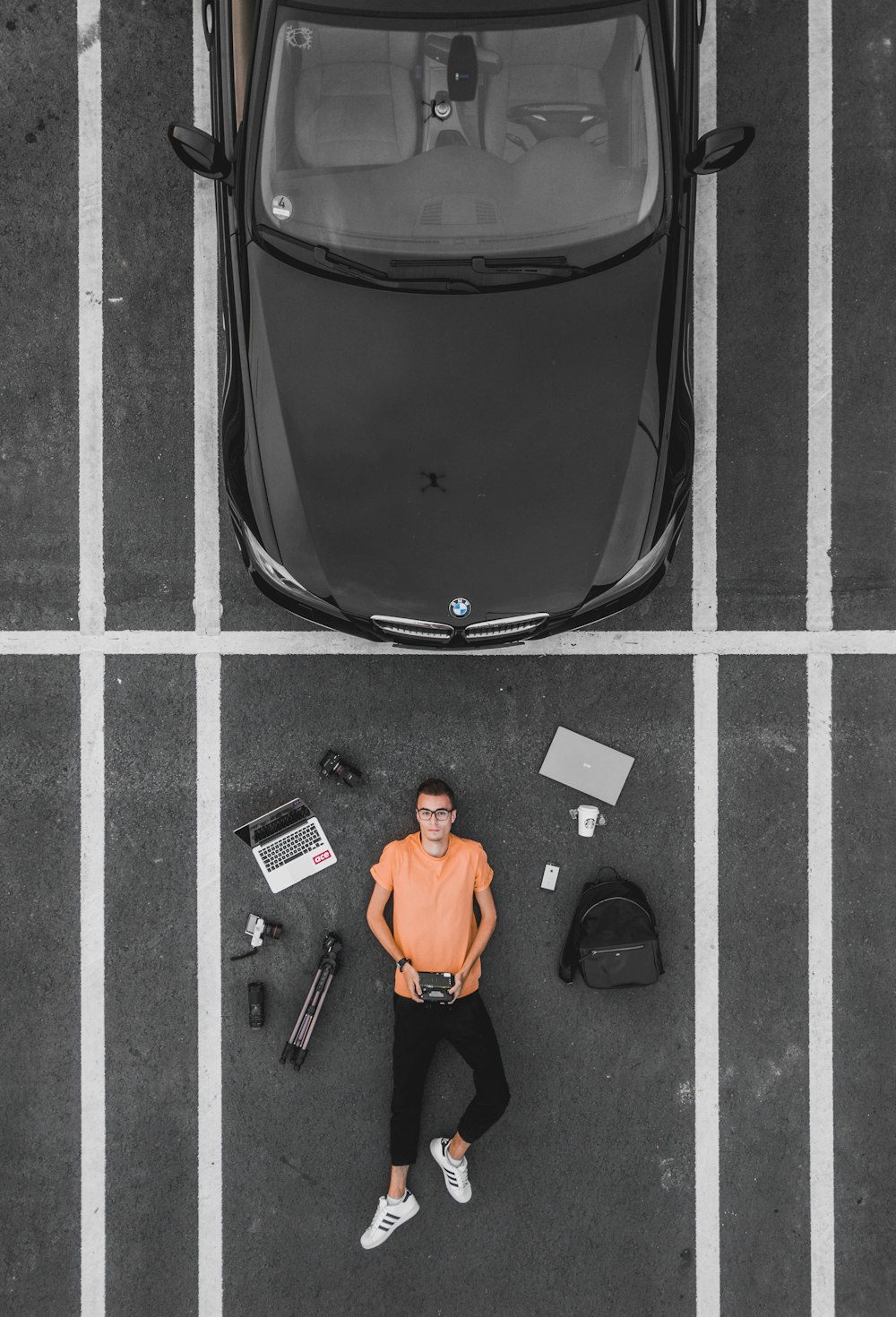 Mann liegt auf Parkplatz in der Nähe von schwarzem Auto