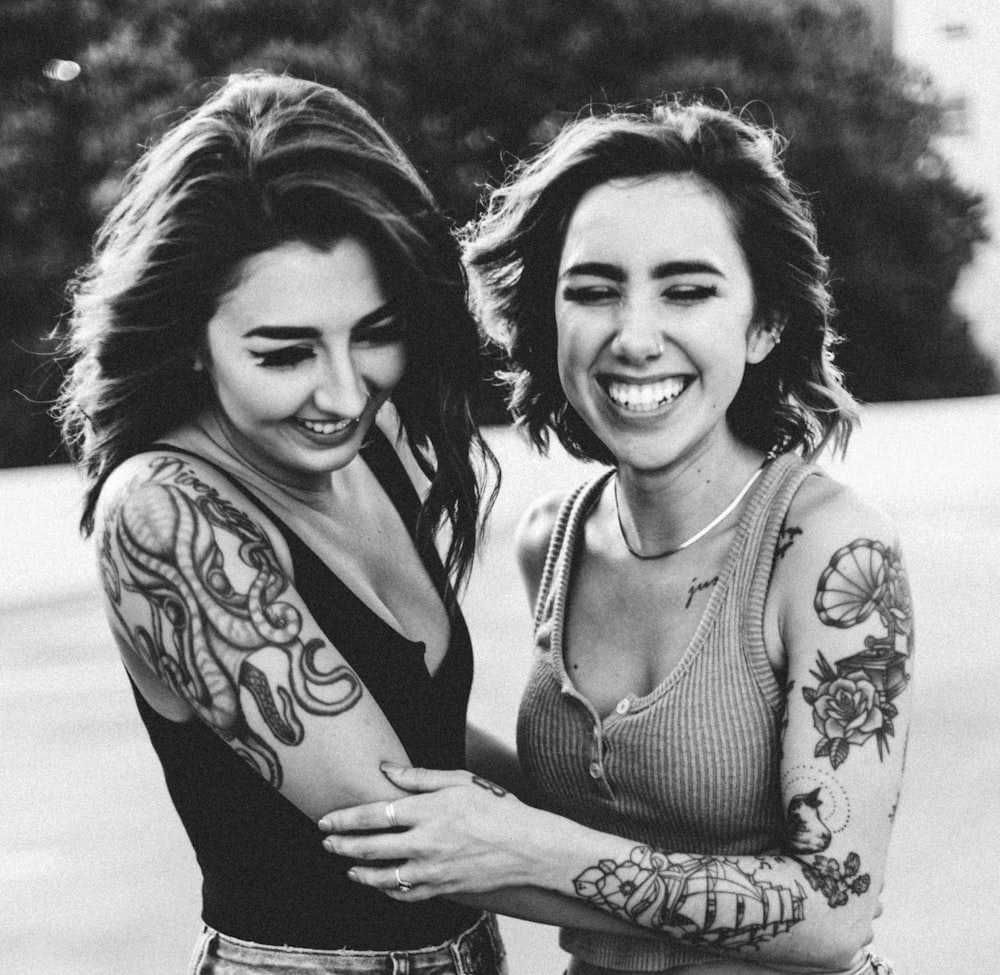 야외에서 서로를 안고 있는 두 여성의 회색조 사진