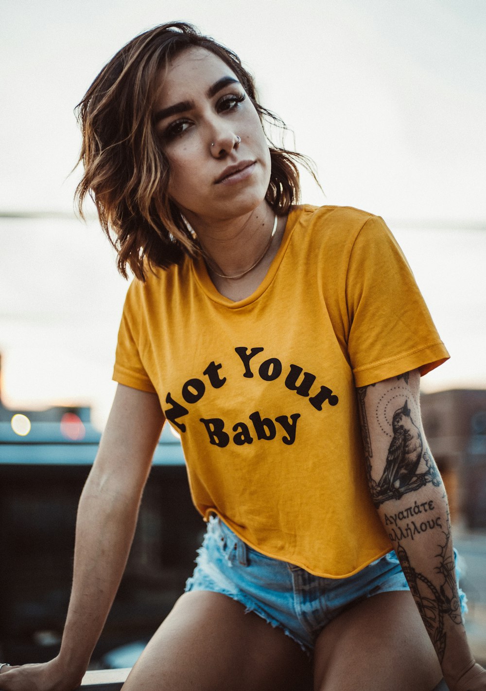 woman in yellow crew-neck shirt and blue short shorts sitting on bench