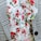 A close-up of a garment featuring a houndstooth checkered pattern next to a floral print with ruffled fabric. The floral pattern includes red and pink flowers with green leaves, creating a contrast against the black and white texture.