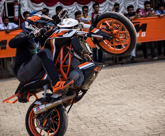 person riding black and white Duke 390 dirt bike on concrete pavement outdoor during daytime