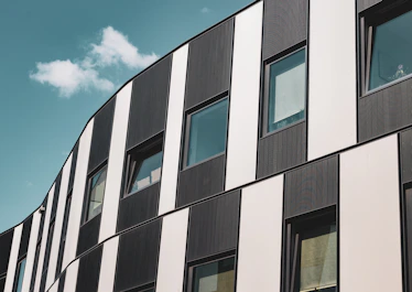 Wide shot of a modern building with sleek black and white facade panels reflecting premium craftsmanship.
