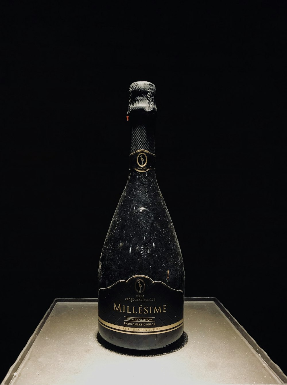 schwarze Millesime-Flasche auf brauner Oberfläche
