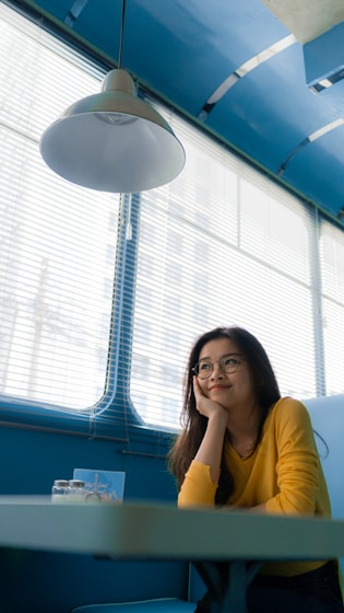 woman resting her chin on her palm while sitting on chair