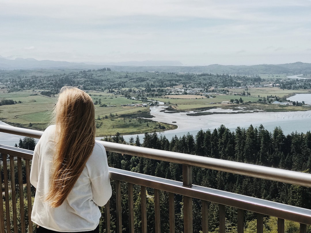 woman standing near the steel railings in front of the mountains during daytime