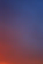 a plane flying in the sky at sunset