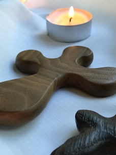 A close-up of a handcrafted wooden cross resting on a soft fabric.