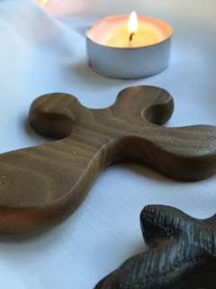 A close-up of a handcrafted wooden cross resting on a soft fabric.