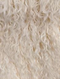 Soft, curly wool or fur with a light, creamy color. The texture appears fluffy and dense, suggesting a natural, warm material.