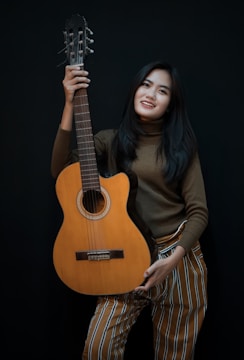 smiling woman while holding cut-away acoustic guitar