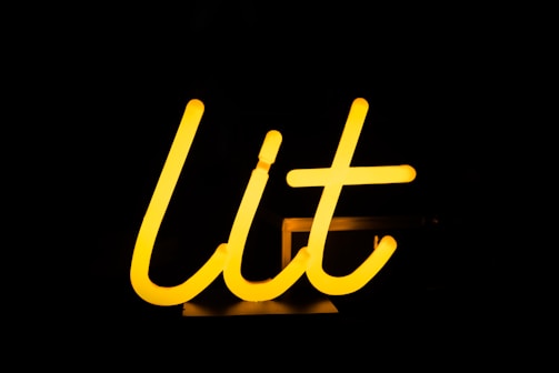 A glowing yellow neon sign spells out the word 'lit' against a dark background.