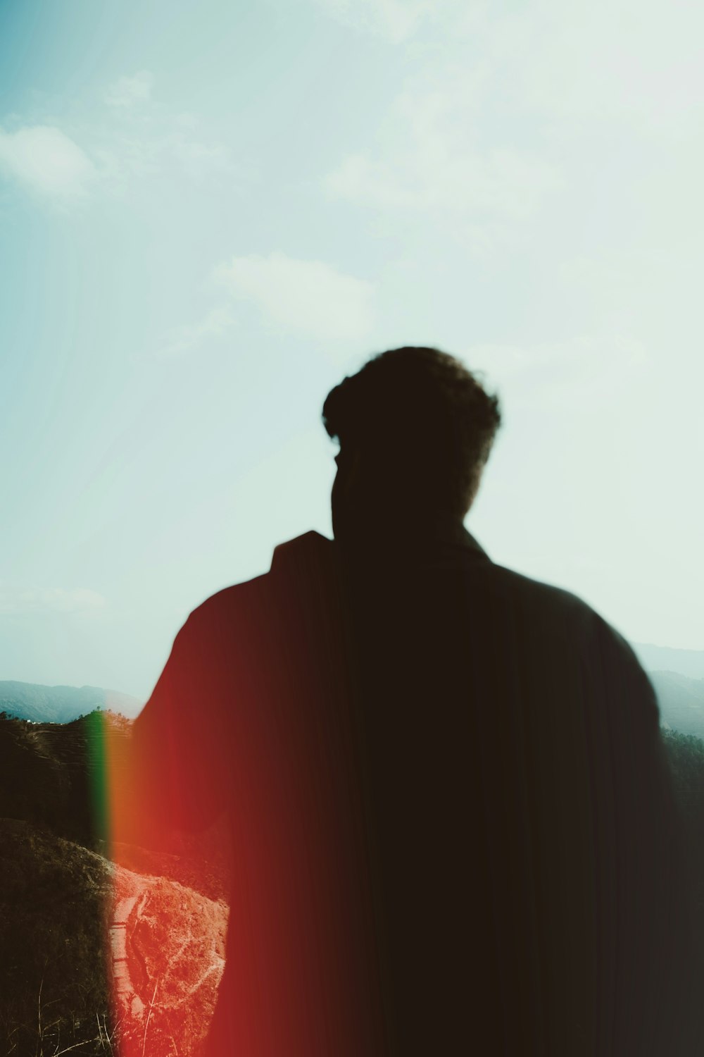 a man standing in a field with a rainbow in the sky