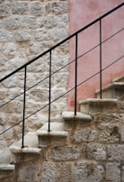 Rustic wooden stair guardrail blending with natural stone walls