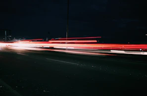 Abstract light trails weaving through a dark urban street at night.