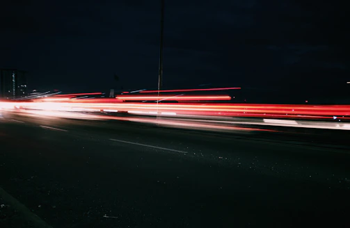 Abstract light trails weaving through a dark urban street at night.