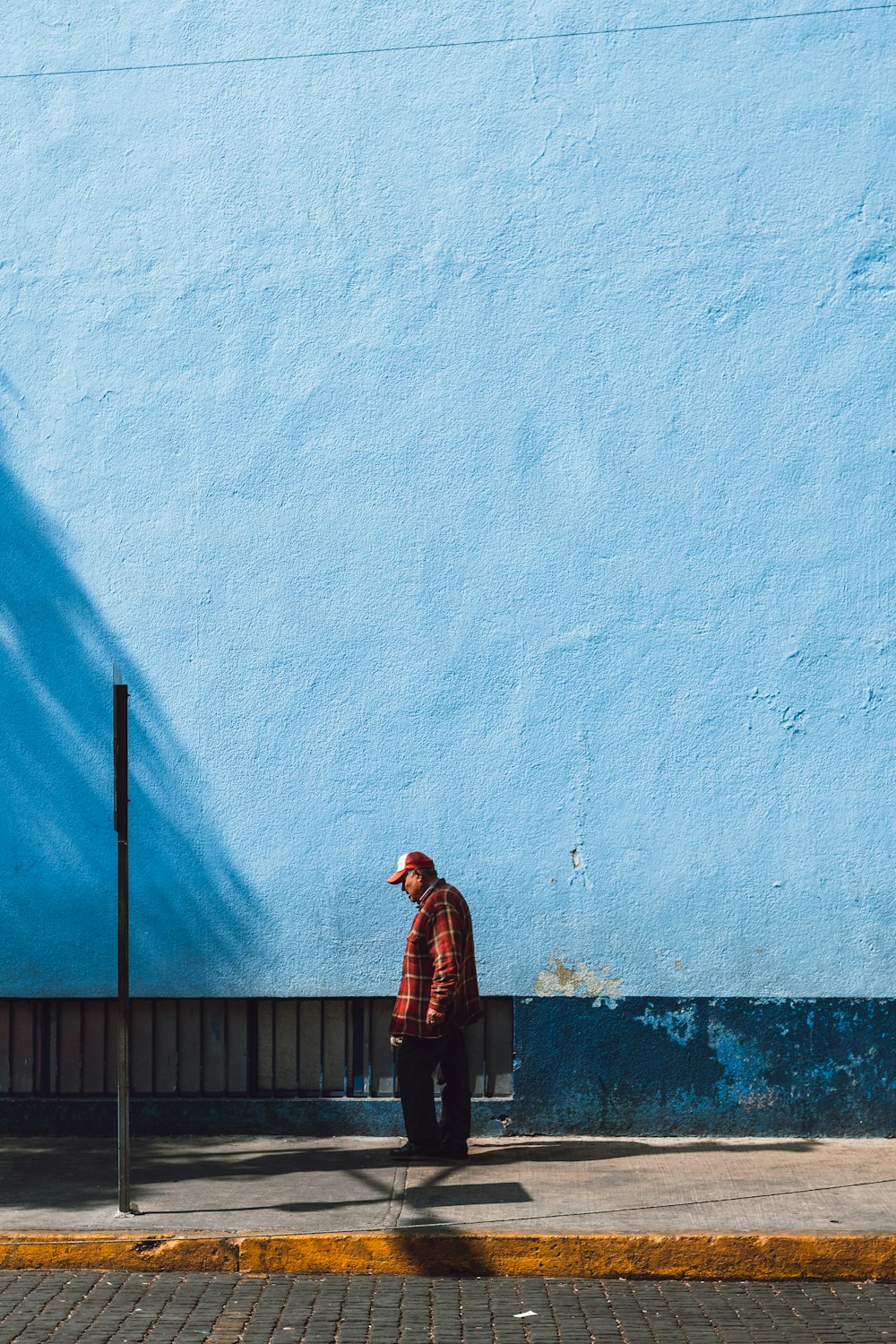 homem em pé perto da parede azul