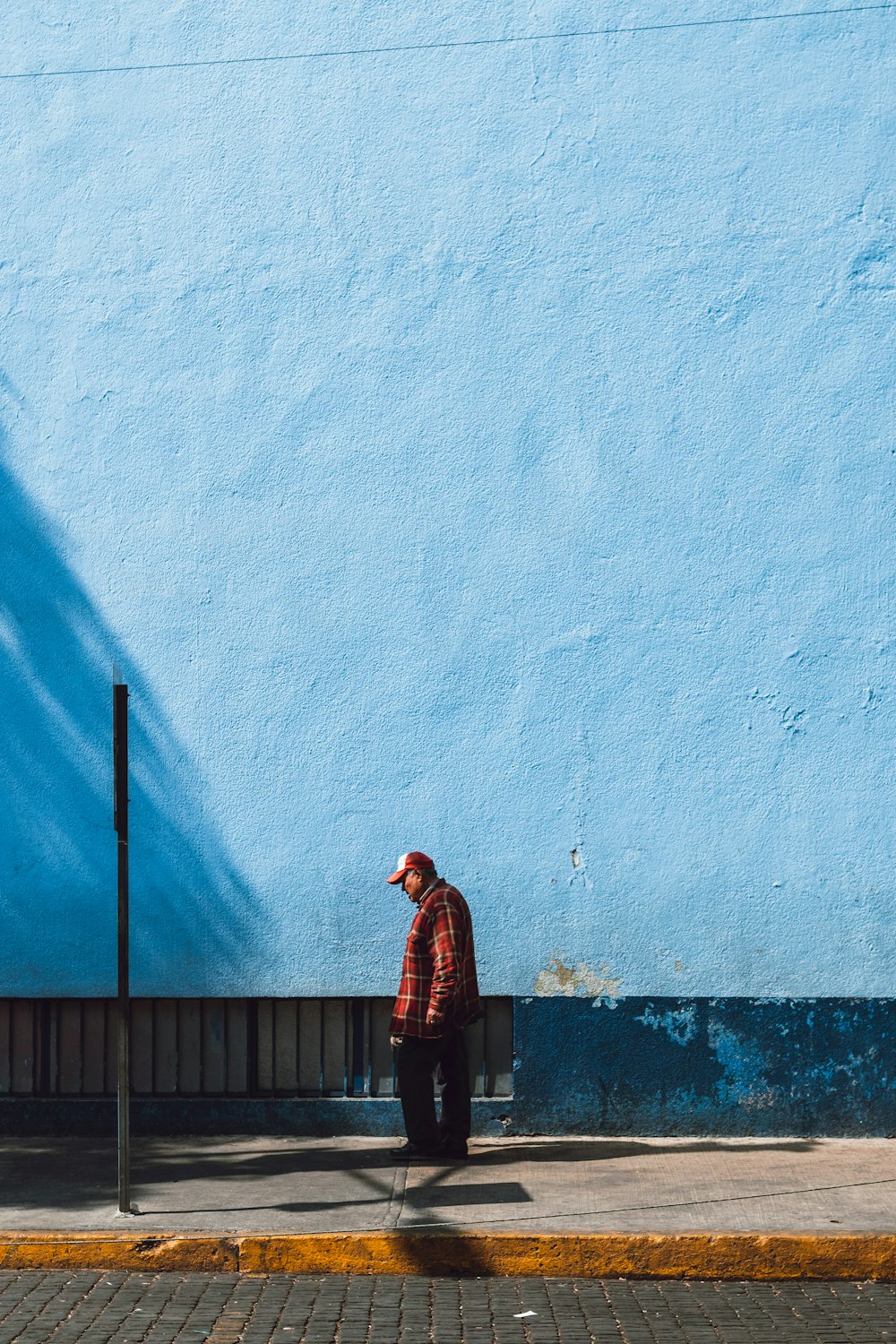 Homme debout près du mur bleu