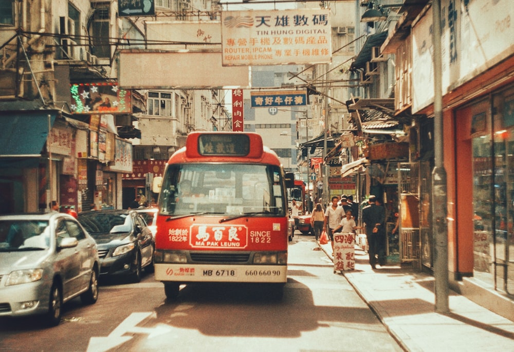 bus rouge près de deux voitures pendant la journée