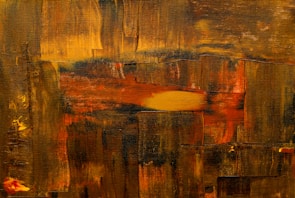 An abstract painting featuring a series of overlapping brushstrokes in various shades of yellow, brown, and red. The brushstrokes create a textured effect on the canvas, providing a sense of depth and complexity. Small patches of bright yellow and orange add contrast and highlight certain areas within the composition.