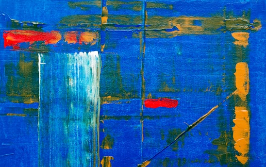 An abstract painting featuring a vibrant blue background with dynamic strokes of orange and red. Vertical and horizontal lines intersect across the canvas, adding structure and depth. A splash of white creates a focal point, contrasted by the bold colors around it.