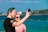 Couple taking a selfie on a cruise ship deck with clear blue sea behind them.
