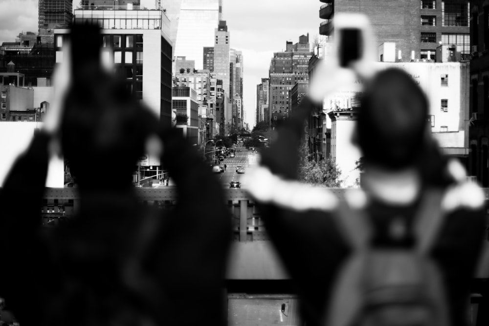 grayscale shot of two persons taking photo of buildings