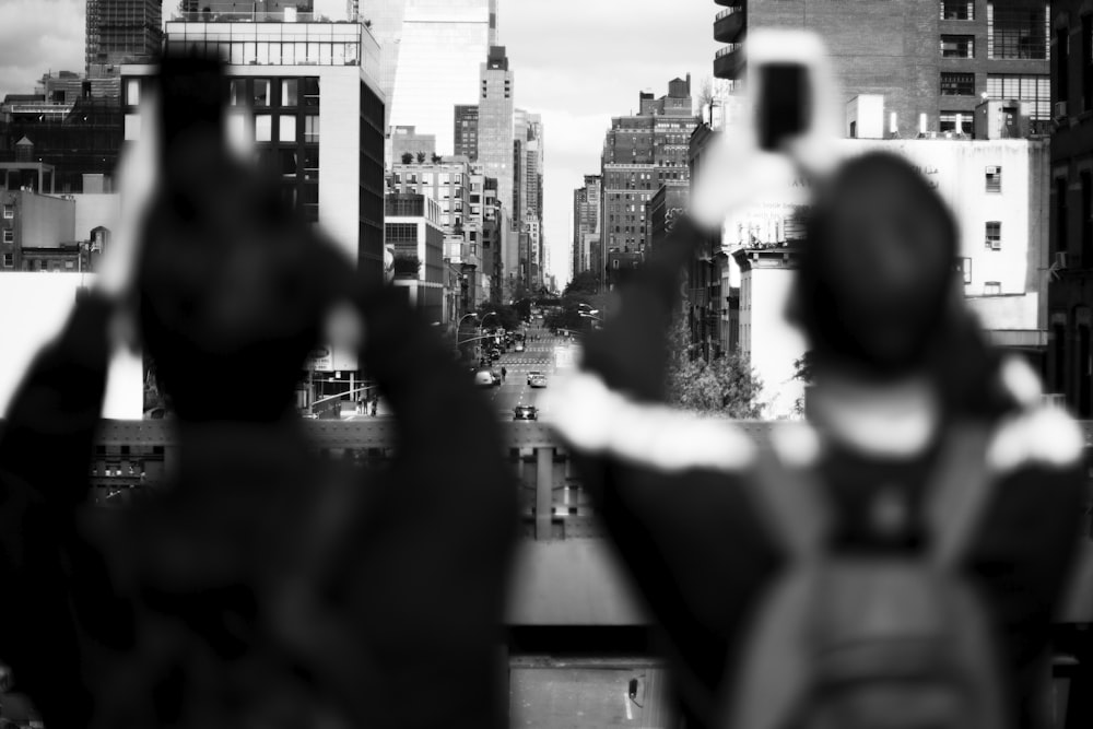 grayscale shot of two persons taking photo of buildings
