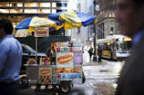Close-up of a steaming Sabrett hotdog topped with mustard and onions on a classic New York street cart.