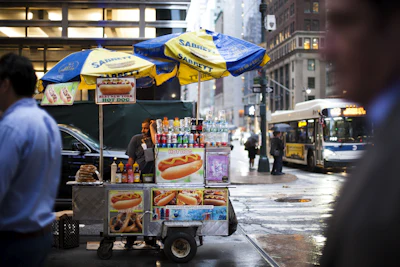 A hot dog vendor cart at a city street intersection