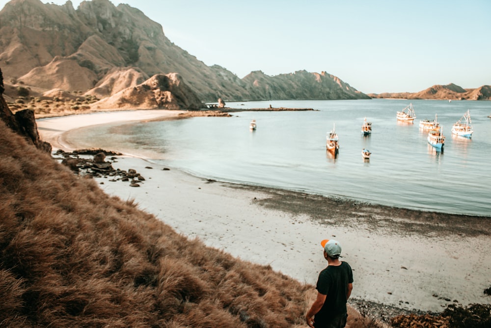 person standing on shore near boats during daytime