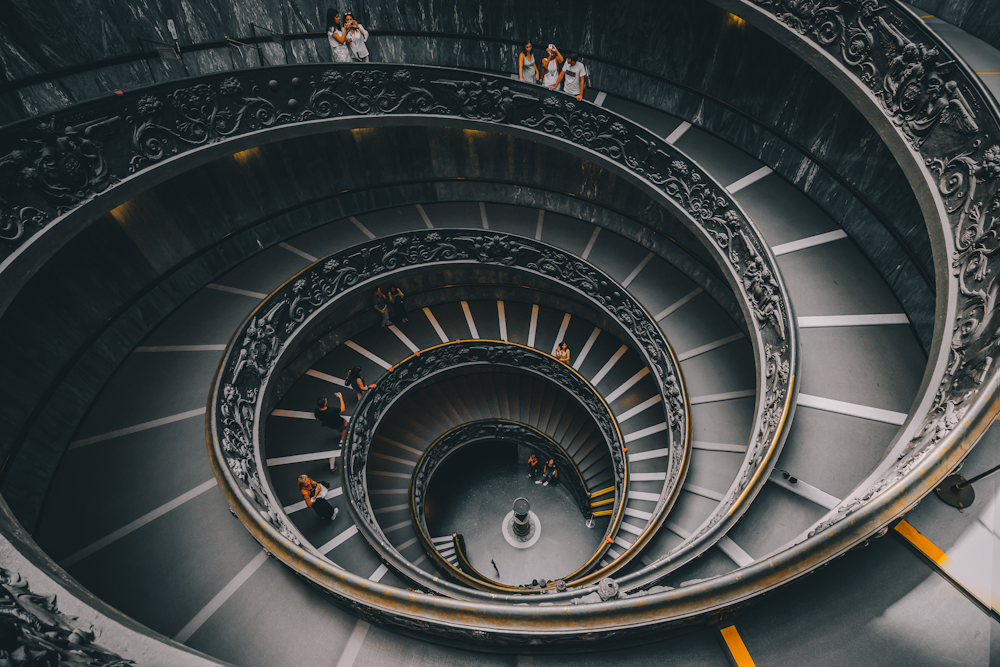 a spiral staircase in a building with people walking down it