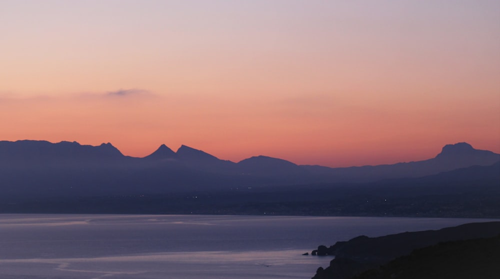 body of water near mountain during golden hour