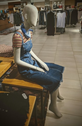 Mannequin dressed in a casual chic outfit featuring a soft cotton blouse and denim jeans under warm lighting.