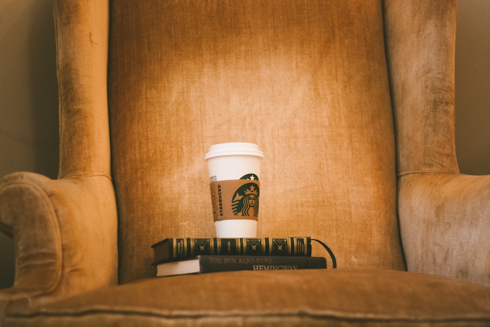 bicchiere di plastica Starbuck bianco su poltrona in tessuto marrone