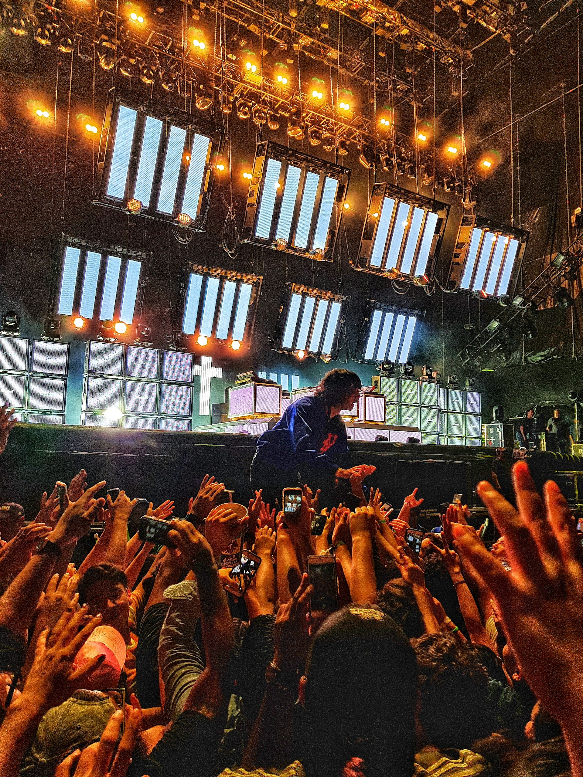 A dynamic hip-hop artist performing on stage with bright lights and an enthusiastic crowd.