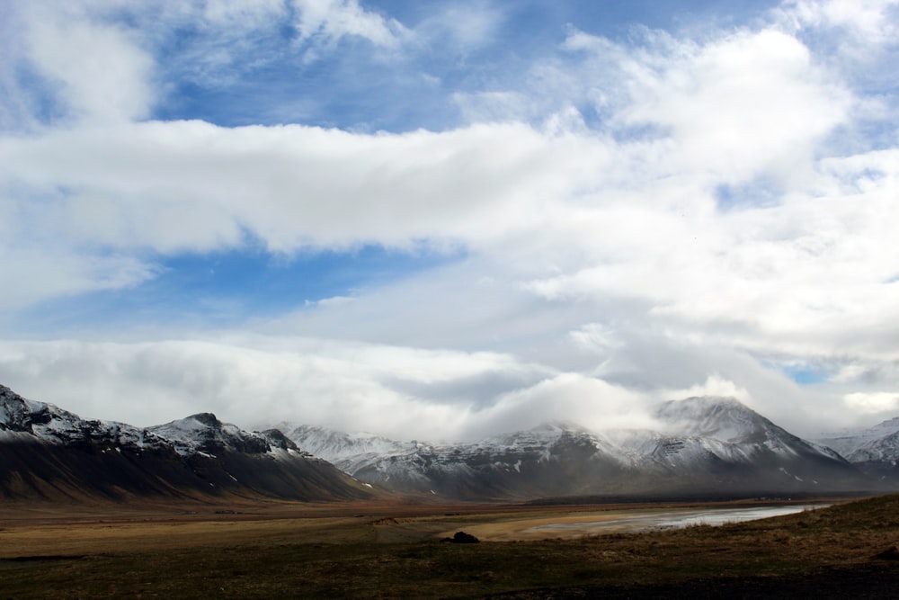 landscape photo of black and white mountains under white and blue sky at daytime